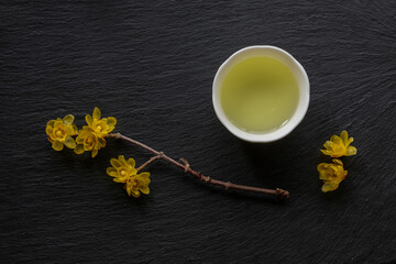 Japanese green tea and Ume (apricot) flowers in a beauty minimalist aesthetic arrangement on black granite board background. Japan.