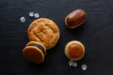 Traditional Japanese sweets, Ume (apricot) flower petals and Japanese green tea in a beauty minimalist aesthetic arrangement on black granite board background. Japan.
