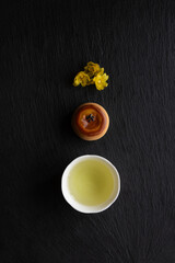 Japanese green tea, Wagashi, Ume (apricot) flowers and  in a beauty minimalist aesthetic arrangement on black granite board background. Japan.