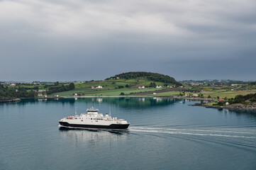 Fototapeta premium A ferry boat, sailing near the beautiful Norwegian coastline, near Stavanger, southern Norway. The water is very calm.