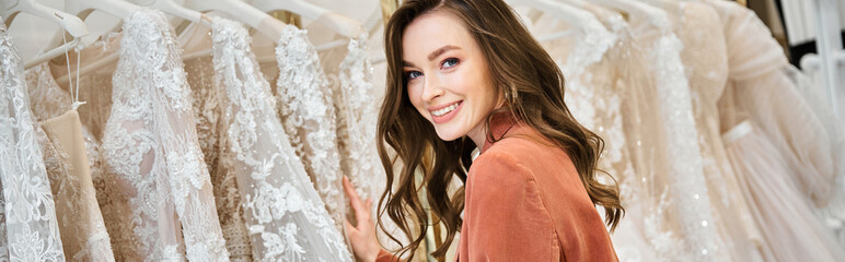 A young bride stands before a selection of wedding dresses, trying to find the perfect gown for her special day. © LIGHTFIELD STUDIOS