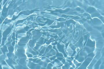 Blue water with ripples on the surface. Defocus blurred transparent blue colored clear calm water surface texture with splashes and bubbles. Water waves with shining pattern texture background.
