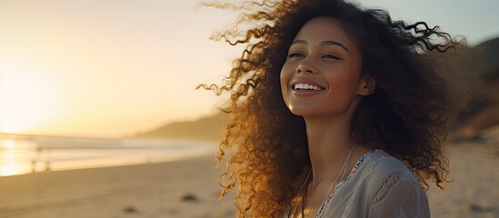 Smiling latin hispanic woman relaxing on beach with closed eyes at sunset Beautiful mixed race woman enjoying wind fluttering hair Charming young woman breathing fresh air at summer beach