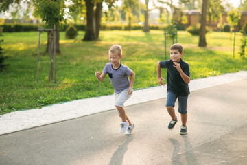 Two children are playing in the park. Two beautiful boys in T-shirts and shorts have fun smiling....