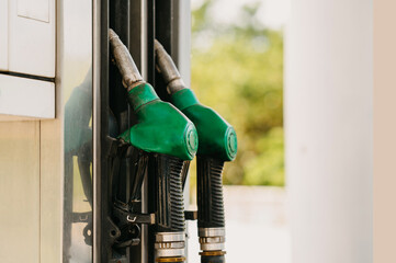 A closeup shot of green fuel pump nozzles at a gas station, indicating readiness to refuel vehicles