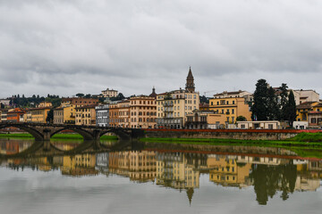 Fototapeta premium Scenic view of the Lungarno Soderini with the Ponte alla Carraia bridge and the top of the Basilica of Santo Spirito on a cloudy spring day, Florence, Tuscany, Italy
