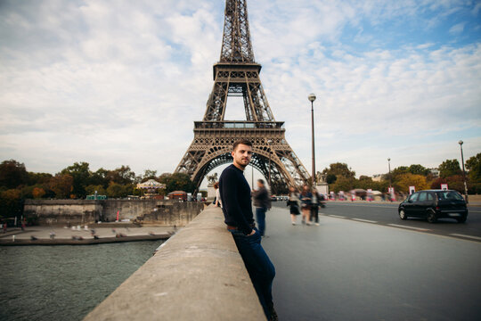 Handsome man in dark pullover is standing on the bridge background of the Eiffel Tower