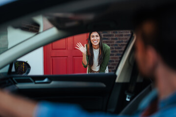 Woman waving from doorway to man in car