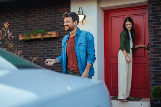 Man leaving home with woman at door