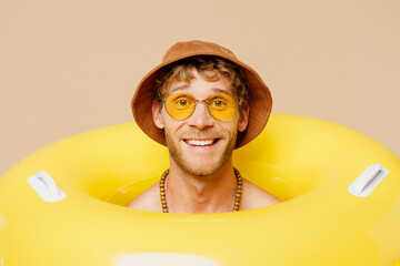 Close up young smiling happy fun man wearing hat yellow inflatable rig relax rest near hotel pool...