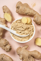 Ground ginger root powder natural spice seasoning on pink background