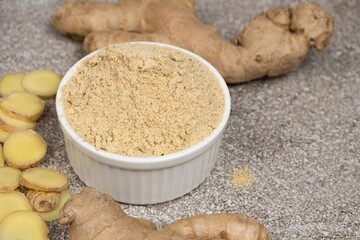 Ground ginger root powder natural spice seasoning on gray stone background