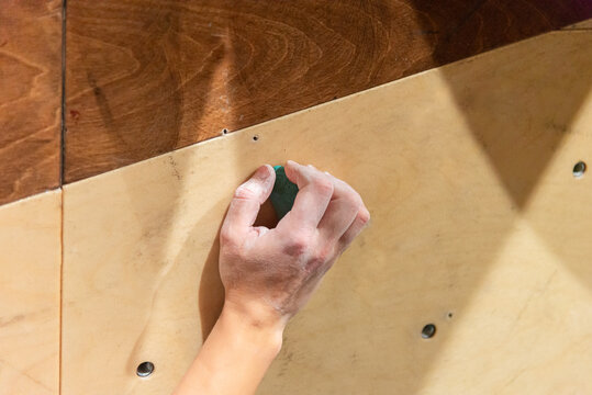 Climber's Hand Gripping Hold on Climbing Wall