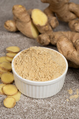 Ground ginger root powder natural spice seasoning on gray stone background