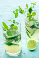 Mojito cocktail party. Summer cold drink with lime, fresh mint, and ice. Cool beverage on a blue background