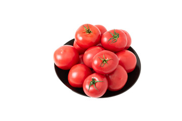 Top view of ripe tomatoes with water droplets lying in a black plate on a white background