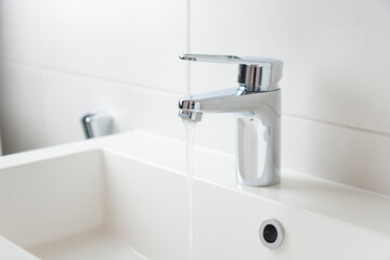 Modern bathroom faucet, water tap with running water and white sink, pure water concept, saving natural recourses concept banner with copy space