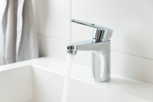 Modern bathroom faucet, water tap with running water and white sink, pure water concept, saving natural recourses concept banner with copy space