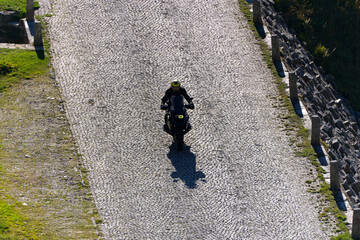 Fototapeta premium Scenic view of mountain pass road named Tremola with motorcyclist way up at Swiss mountain pass Gotthard on a sunny late summer day. Photo taken September 10th, 2023, Gotthard, Switzerland.