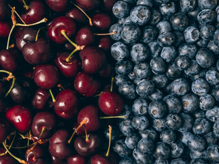 Mix of fresh ripe sweet cherry and blueberries background. Closeup, top view.