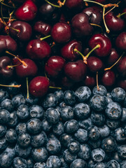 Mix of fresh ripe sweet cherry and blueberries background. Closeup, top view.