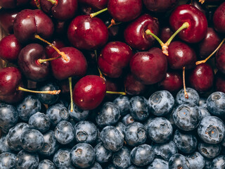 Mix of fresh ripe sweet cherry and blueberries background. Closeup, top view.