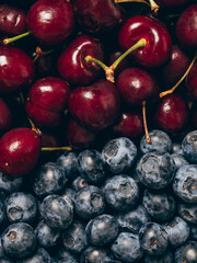 Mix of fresh ripe sweet cherry and blueberries background. Closeup, top view.