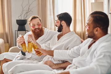 Three cheerful men in bathrobes sit on a couch, sharing laughter and drinks while enjoying each others company.