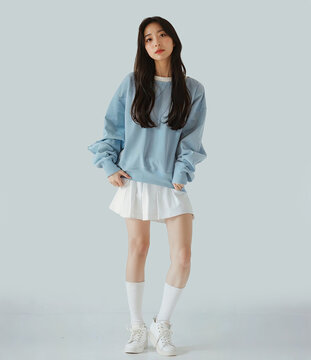 Full Body Photo of Asian woman in Light Blue Loose Sweatshirt and White Short Skirt Posing Against Simple Background