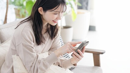 リビングでスマホを見る女性