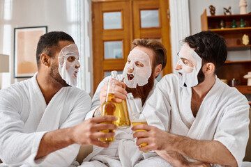 Three diverse men in bathrobes, masks on, enjoying beers together.