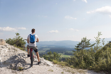 Mountain bike rider riding an electric bike along a white gravel trail on a sunny summer day....