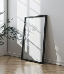 Black framed poster leaning against wall, sunlight through window reflection