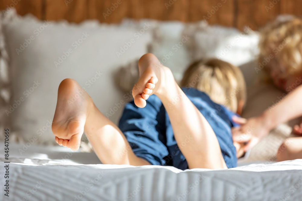 Poster cute sweet toddler children, tickling feet on the bed, laughing and smiling