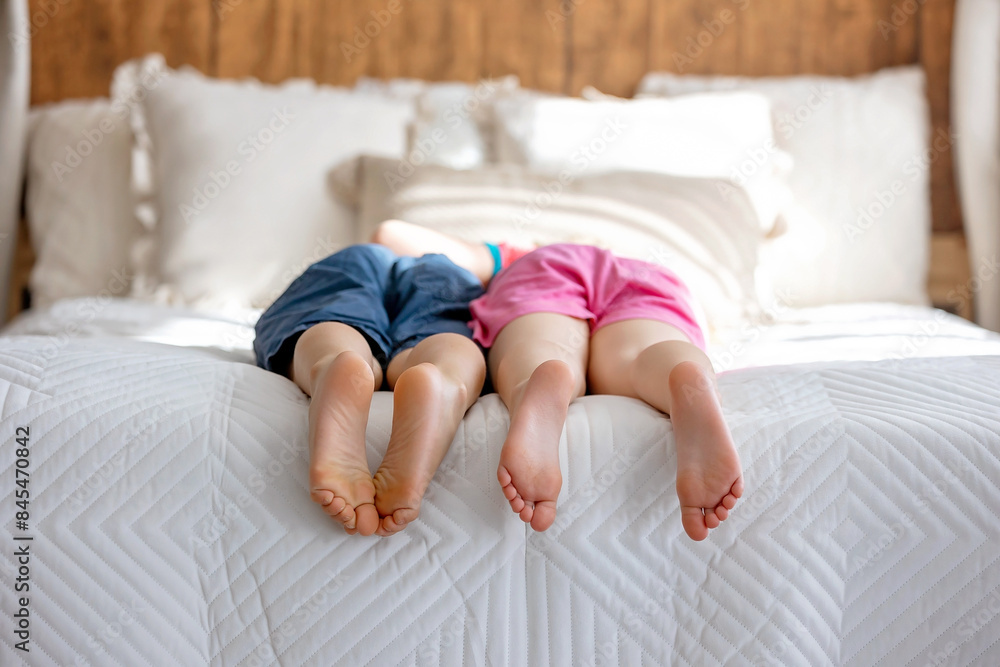 Poster cute sweet toddler children, tickling feet on the bed, laughing and smiling