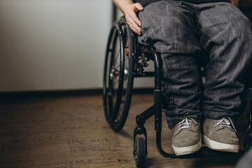 Young man with disability looking through window while sitting on wheelchair in room