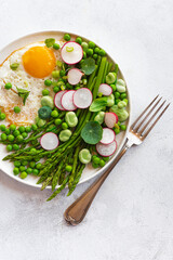 Asparagus green balanced lunch, dietary summer spring plate with asparagus, green peas, fava beans, nasturtium leaves, mint, radish, egg. Low-calorie, low-sugar lunch. New French cuisine, close up