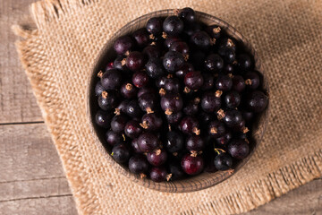 Black currant in a bowl on wooden background. Organic berries. 