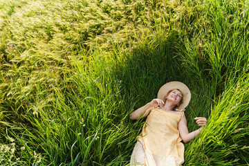 Smiling young woman lying on green grass.