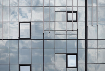 Fototapeta premium empty glass windows of a modern building with a reflection of the sky in the glass