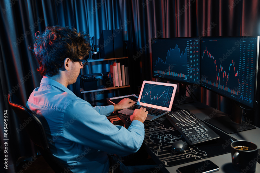 Poster young investor stock trader searching on laptop comparing with dynamic exchange rate screens of curr