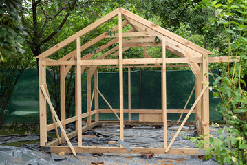 Construction of a large wood greenhouse in garden. Wooden domestic greenhouse for growing vegetables or flowers