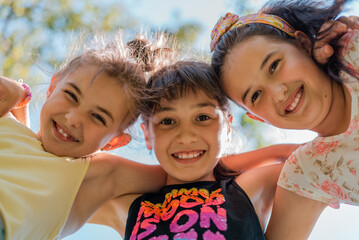 Close up face of happy children embracing each other and smiling at camera, group of joyful kids playing together outside.