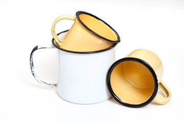 White enamelware cup with two smaller enamelware cups, isolated on white background with copy space