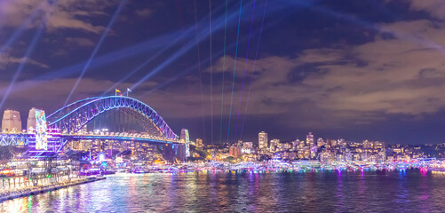 Colourful Light show at night on Sydney Harbour NSW Australia. The bridge illuminated with lasers and neon coloured lights  Vivid Sydney Laser and Light Drone show