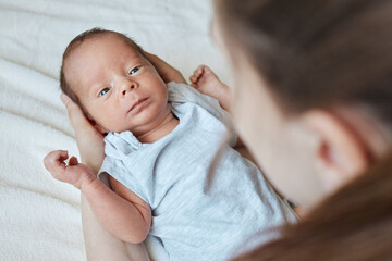 Caring unrecognizable mother cradling her tiny daughter or son at home funny newborn kid in lovely mommy hands woman taking care of her child with love and gentle