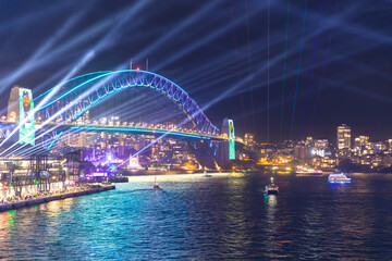 Colourful Light show at night on Sydney Harbour NSW Australia. The bridge illuminated with lasers and neon coloured lights  Vivid Sydney Laser and Light Drone show