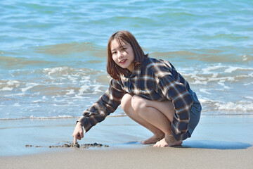 砂浜に文字を書く若い女性