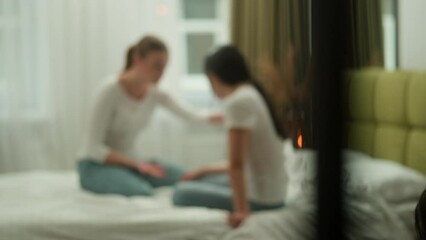 Blurry view unfocused blurred two girls multiracial friends females women on bed home bedroom talking discuss console calming problem communication friends friendship trouble support talk conversation