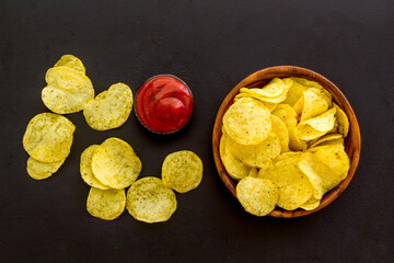 Wooden bowl of crispy potato chips, top view. Fast food and snack background